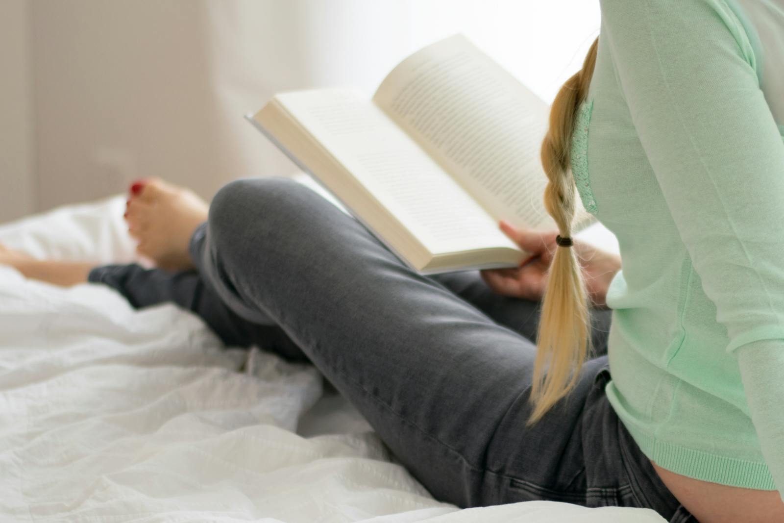 Woman relaxes while reading a book in a cozy indoor setting, exuding tranquility.